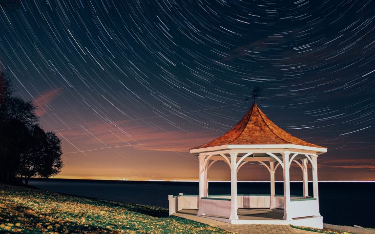 time lapse of stars whirling in a circle behind a white painted pavilion